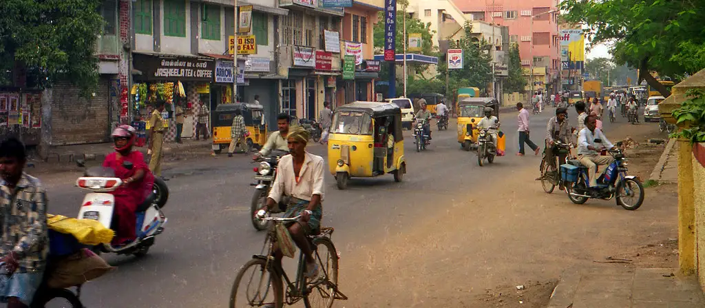 Street in Chennai with auto-rickshaws, cyclists and shopfronts